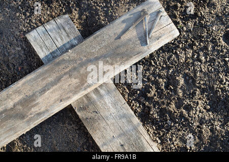 Hölzerne Kreuz Verlegung auf dem Boden mit drei Nägel in der Nähe Stockfoto