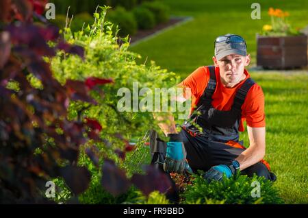Der Garten Designer. Junge kaukasischen Gärtner Blick auf sein Werk. Stockfoto