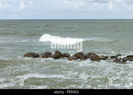 Steinen liegen in einem tobenden Meer unter Schlägen der großen Wellen Stockfoto