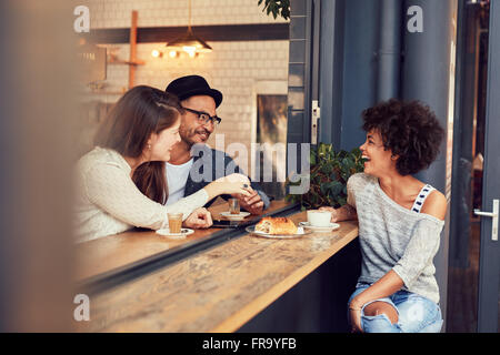 Porträt der glückliche junge Menschen sitzen zusammen in einem Café mit etwas zu essen und Kaffee. Gruppe von Freunden in einem Café treffen Stockfoto