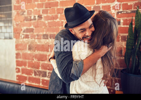 Porträt des jungen Mann umarmt seine Freundin im Café. Junger Mann umarmt eine Frau in einem Café. Stockfoto