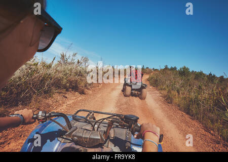 Junge Leute fahren von Quads mit Mann vor. Mann und Frau auf Land fahren auf ein all-Terrain-Fahrzeug. Stockfoto