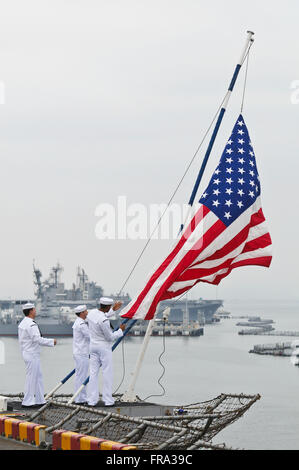 Matrosen an Bord der USS Peleliu (LHA-5) senken die Flagge, wie das Schiff von 32nd Street Naval Station in Gang kommt Stockfoto