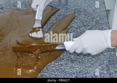 Handwerkliche Herstellung von Pralinen - Temperieren von Schokolade zur Deckung Stockfoto