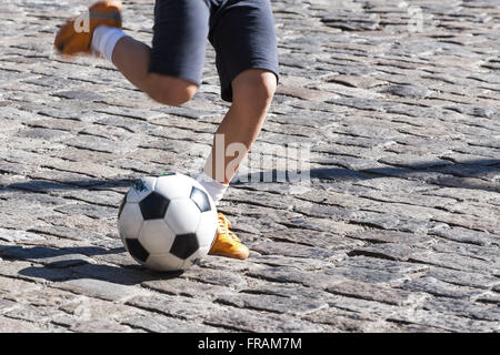 Jungen spielen Ball auf der Straße Stockfoto