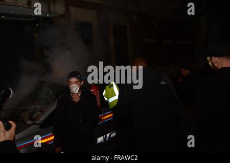 5. November 2015. London, UK. Demonstrant in Gesichtsmaske steht neben dem brennenden Fahrzeug, wie ein Polizist das Feuer greift. © Marc Ward/Alamy Stockfoto