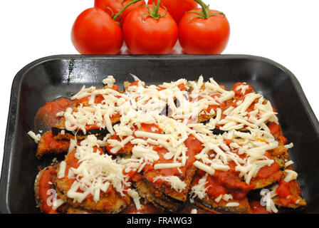 Topf mit Auberginen Parmesan mit Tomaten im Hintergrund Stockfoto