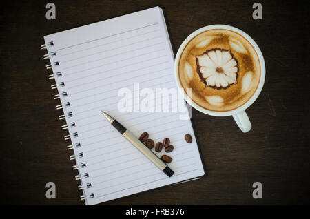 Latte Art Kaffee und Notebook auf hölzernen Hintergrund Stockfoto