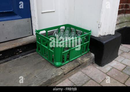 Leere Milchflaschen abgebildet in einem grünen Rack auf einer Stufe in Winchester, Hampshire, UK. Stockfoto