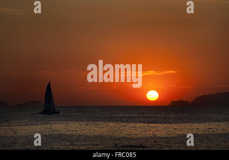 Silhouette eines Segelbootes bei Sonnenuntergang am Strand von Ipanema Stockfoto