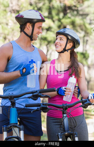 Glückliches Paar hält Wasserflaschen im Wald Stockfoto