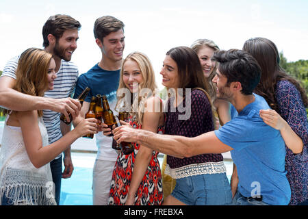 Gruppe von Freunden toasten Bierflaschen in der Nähe von Pool Stockfoto