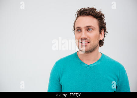 Closeup Portrait glücklich attraktive junge Mann im blauen Pullover nachschlagen und lächelnd auf weißem Hintergrund Stockfoto