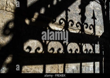 Schatten der alten geschmiedet schwarzen Zaun an der Wand Stockfoto