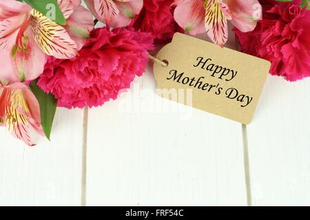 Muttertag Geschenk-Tag unter den oberen Rand des rosa Nelke und Lilie Blumen vor weißem Hintergrund Holz Happy Stockfoto