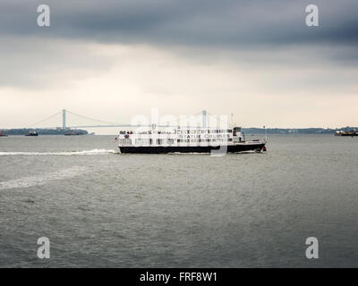 Statue Cruises Touristenboot mit Verrazano-Narrows-Brücke im Hintergrund, New York, USA. Stockfoto