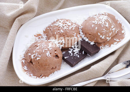 Drei Kugeln Eis vegane Schokolade mit Kokos-Streuseln und Stücke gebrochene Schokolade. (Kokosnuss-Milch, Kakao-Pulver) Stockfoto
