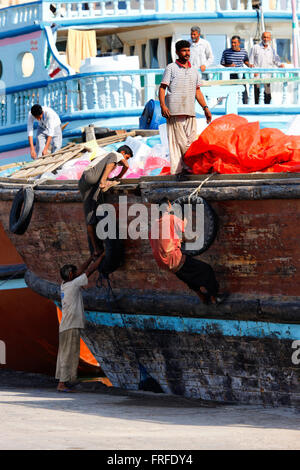 Dubai - Sharjah. Arbeiter Klettern auf einer Ladung Schiff im Hafen von Sharjah, Vereinigte Arabische Emirate Stockfoto