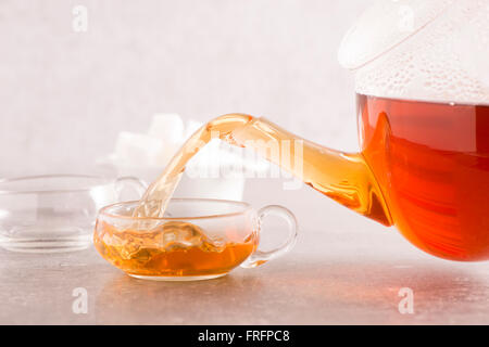 Heißen Tee Teetasse aus Glas Teekanne gießen. Moderne Küche mit Steintisch. Stockfoto