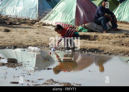 Idomeni, Griechenland, 22. März 2016. Ein Kind spielt mit einem Papierboot in einem provisorischen Lager für Flüchtlinge und Migranten an der griechisch-mazedonischen Grenze, in der Nähe des Dorfes Idomeni. Bildnachweis: Orhan Zolak / Alamy Live News Stockfoto