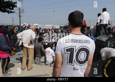 Idomeni, Griechenland, 22. März 2016. Ein Mann mit einem Deutschland Fußball Team Replica T-shirt schaut eine "Offene Grenzen" Sit-in Protest gegen Gleisanlagen in einem provisorischen Lager für Flüchtlinge und Migranten an der griechisch-mazedonischen Grenze, in der Nähe des Dorfes Idomeni. Bildnachweis: Orhan Zolak / Alamy Live News Stockfoto