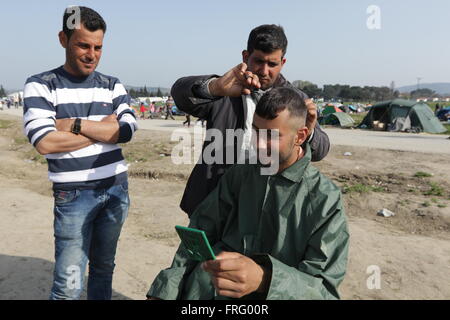 Idomeni, Griechenland, 22. März 2016. Ein Mann bekommt einen Haarschnitt in einem provisorischen Lager für Flüchtlinge und Migranten an der griechisch-mazedonischen Grenze, in der Nähe des Dorfes Idomeni. Bildnachweis: Orhan Zolak / Alamy Live News Stockfoto