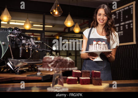 Lächelnde Barista Halteplatte mit Kuchen Stockfoto