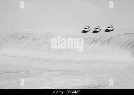 drei 4 x 4 Autos Alligned und bereit, von einer großen Sanddüne in der Wüste Sahara in schwarz und weiß, Tunesien herabzusteigen, Stockfoto