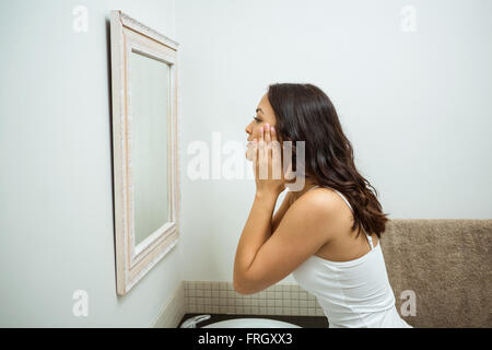 Frau Kontrolle ihrer Haut im Badezimmer Stockfoto