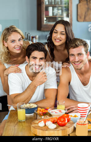 Lächelnde junge Paare am Frühstückstisch in der Küche Stockfoto
