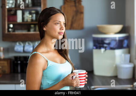 Nachdenkliche Frau mit Kaffeetasse in Küche Stockfoto