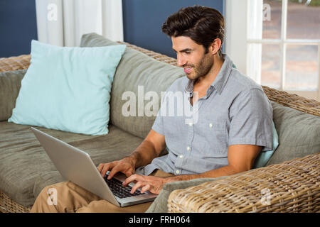 Junger Mann mit Laptop im Wohnzimmer Stockfoto