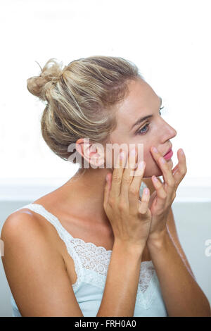 Frau Kontrolle ihrer Haut im Badezimmer Stockfoto