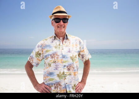 Älterer Mann in Sonnenbrille und Hut stehen auf dem Strand Stockfoto