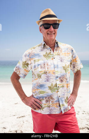 Älterer Mann in Sonnenbrille und Hut stehen auf dem Strand Stockfoto