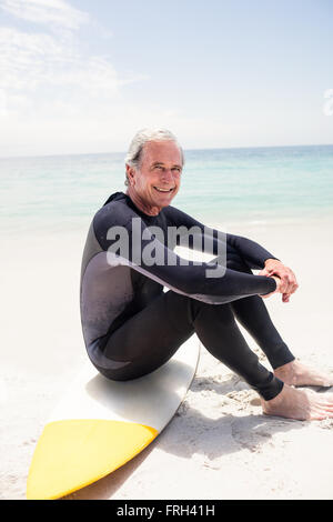 Porträt von senior glücklich im Neoprenanzug sitzt auf Surfbrett Stockfoto