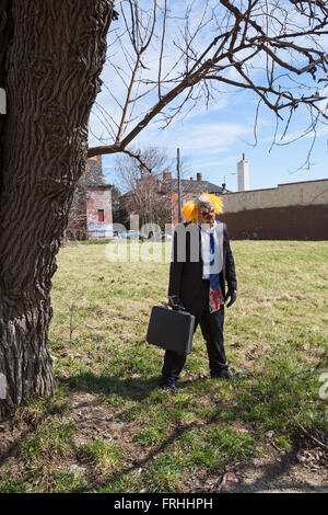 Detroit, Michigan - ein Mann, gekleidet wie ein Irrer Clown in ein unbebautes Grundstück entlang der Marche du Nain Rouge steht. Stockfoto