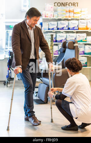 Mann versucht Krücken in einer Apotheke. Stockfoto