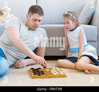 Kleine Mädchen und ihr Vater spielen Dame. Stockfoto