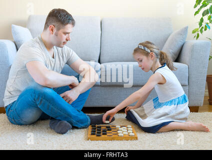 Kleine Mädchen und ihr Vater spielen Dame. Stockfoto