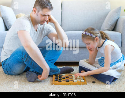 Kleine Mädchen und ihr Vater spielen Dame. Stockfoto