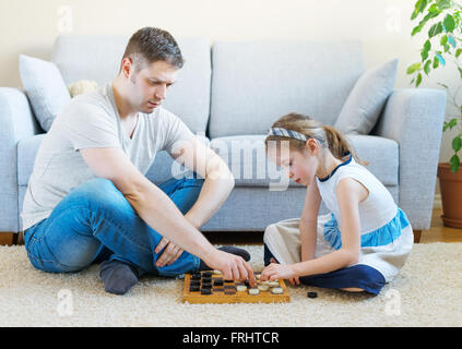 Kleine Mädchen und ihr Vater spielen Dame. Stockfoto