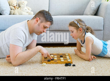 Kleine Mädchen und ihr Vater spielen Dame. Stockfoto