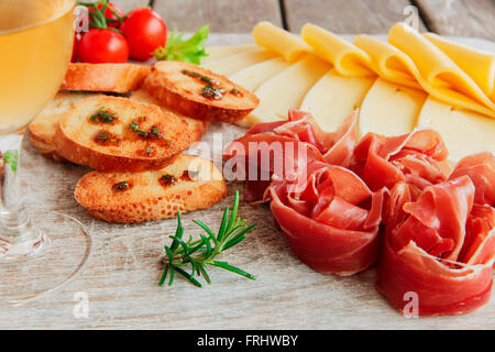 köstliche Vorspeise Wein - Schinken, Schinken, Käse, Kapern, Tomaten, serviert auf einem Holzbrett Licht Stockfoto