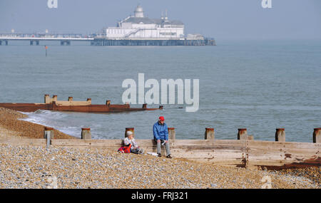 Ein paar sitzt am Strand in schönen Sonnenschein Frühlingswetter in Eastbourne East Sussex UK Stockfoto