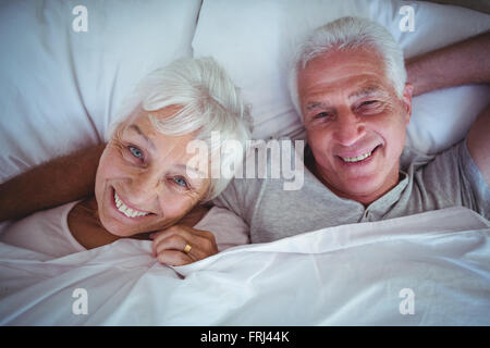 Gerne älteres Paar auf Bett liegend Stockfoto