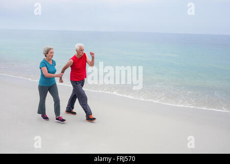 Älteres paar jogging am Strand Stockfoto