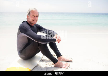 Porträt von senior glücklich im Neoprenanzug sitzt auf Surfbrett Stockfoto