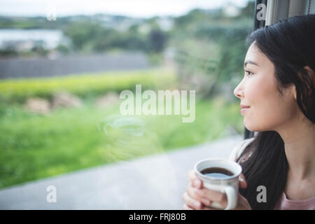 Glückliche Frau Blick durch Fenster Stockfoto