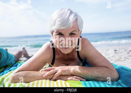 Porträt der glückliche ältere Frau, die am Strand liegen Stockfoto